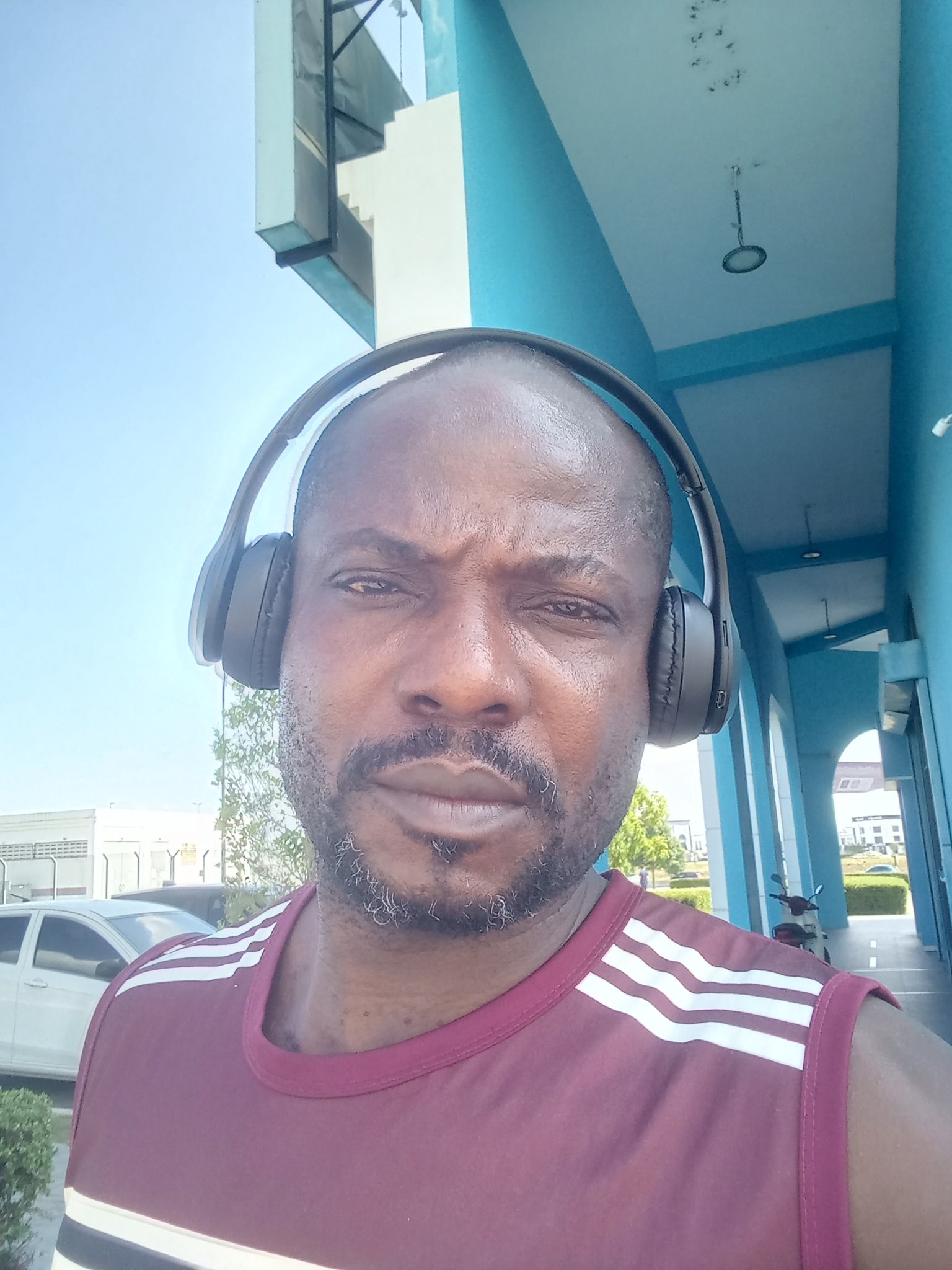 Outdoors, headphones on, blue building