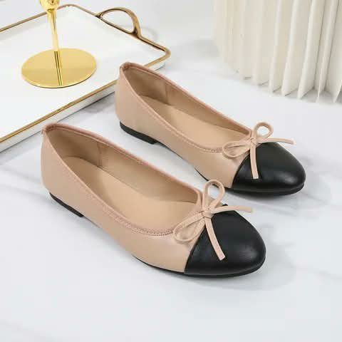Beige flats with black toes and bow details.