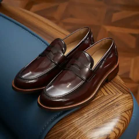Burgundy penny loafers resting on wood.