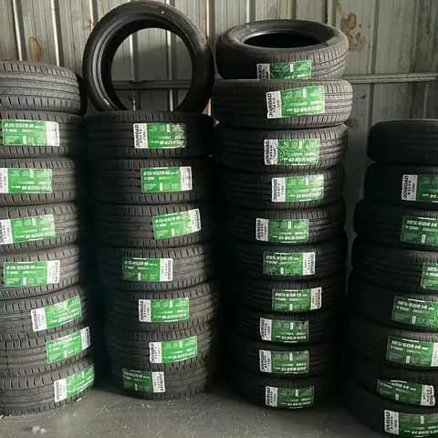 Stacks of car tyres with green labels in a warehouse