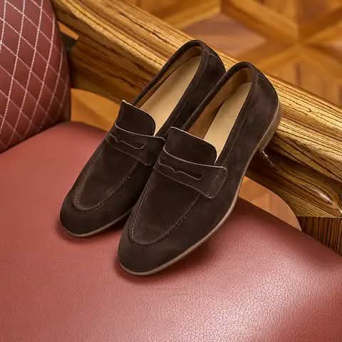 Dark brown suede penny loafers on a chair.