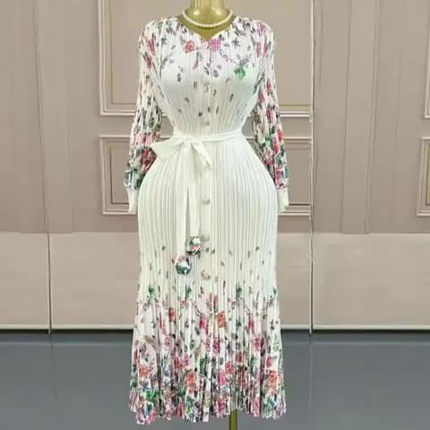 A long white pleated dress with a floral print at the hem and sleeves and a sash belt, on a mannequin.