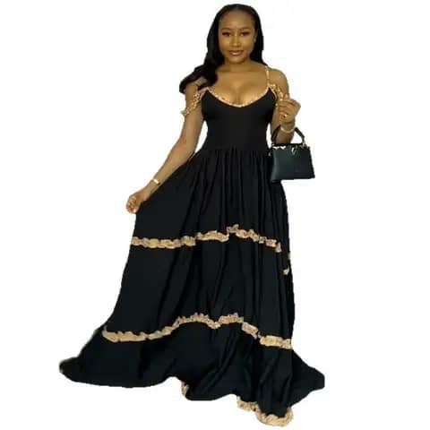 A woman wearing a black tiered maxi dress with gold trim at the neckline and tiers.