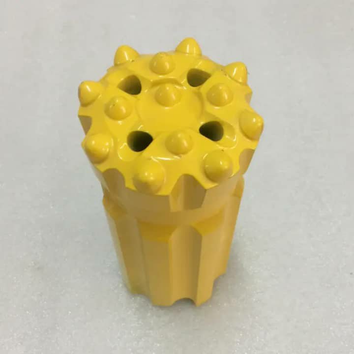 A single yellow button-type drill bit with rounded studs on the face.