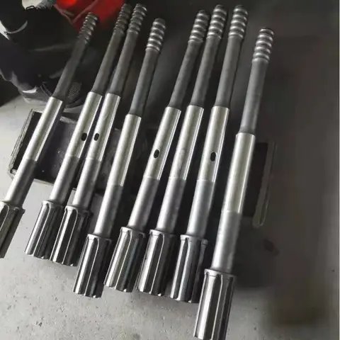 Six dark drill rods standing in a row.