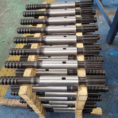 Many silver drill rods stacked on a wooden pallet.