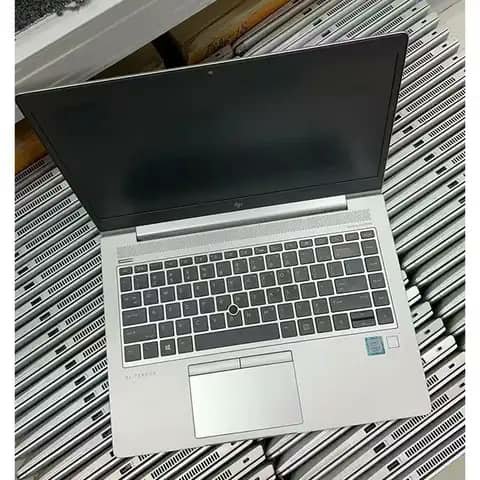 Silver HP EliteBook open on a stack of laptops