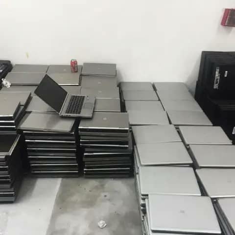 Stacks of HP laptops in a warehouse, one open