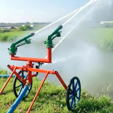 Wheeled irrigation sprinkler cart with twin spray cannons working in a field
