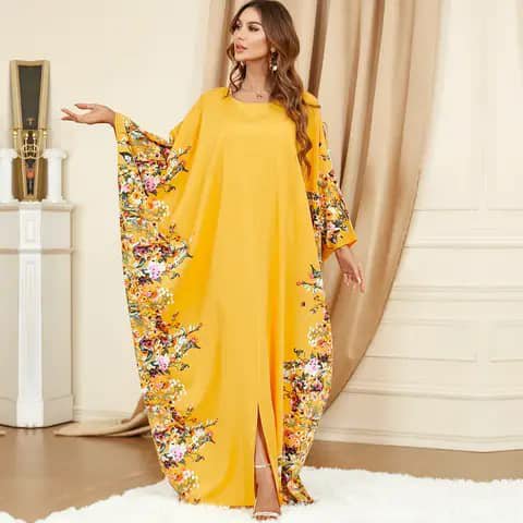 A woman wearing a long yellow kaftan with floral-patterned sleeves.