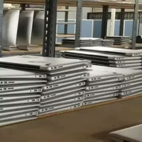 Stacks of silver laptops on warehouse shelves