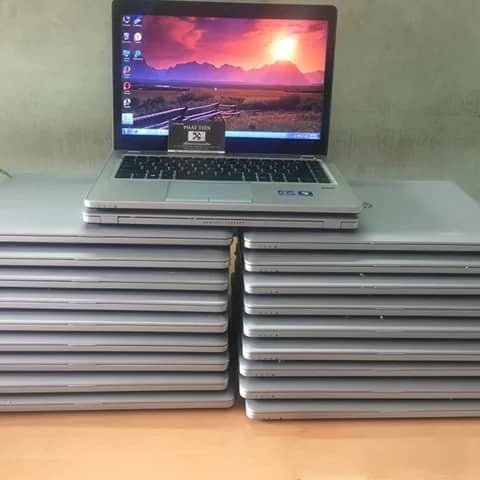 Two stacks of silver laptops with one open showing its screen