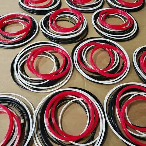 Many seal ring sets in red, black and white laid out on cardboard.