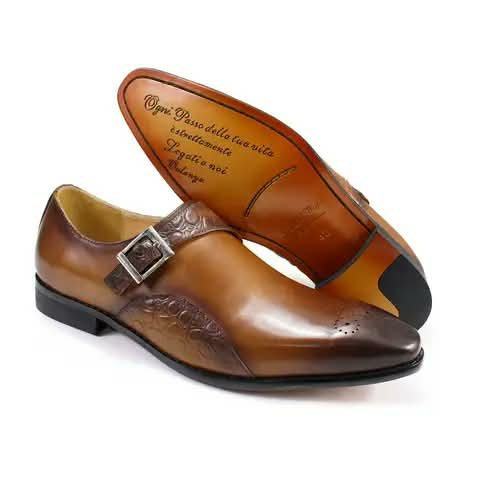 A tan monk strap shoe, its sole printed with lettering.